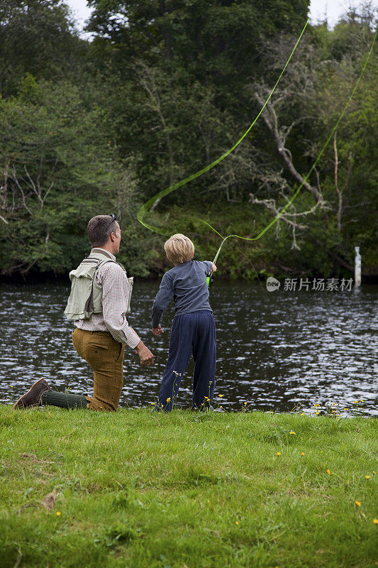 儿子和爸爸在河上学钓鱼