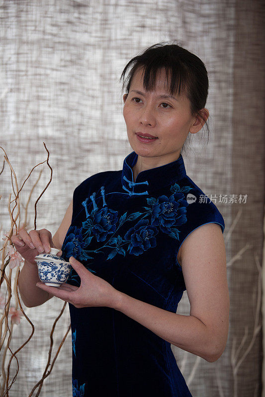 穿着旗袍，手持瓷杯的中国妇女