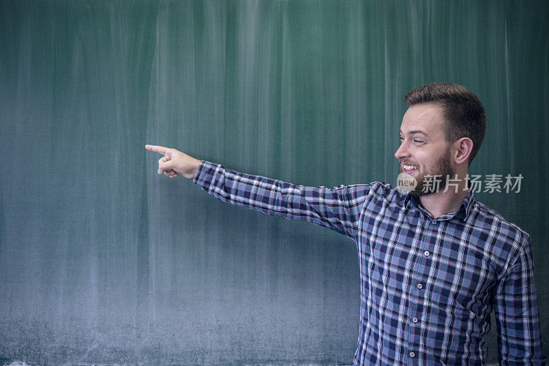 年轻的学生微笑着指着学校黑板的复制空间