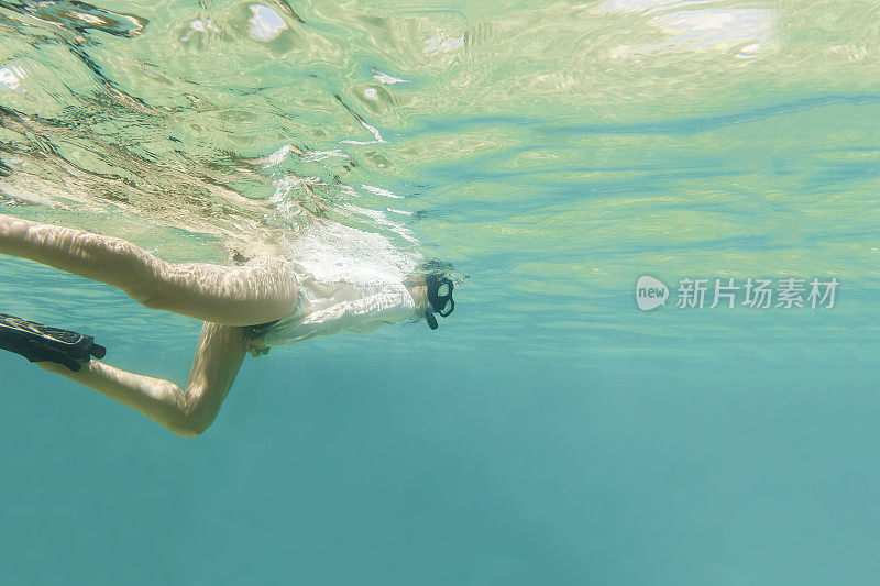 女人浮潜在清澈的绿松石水