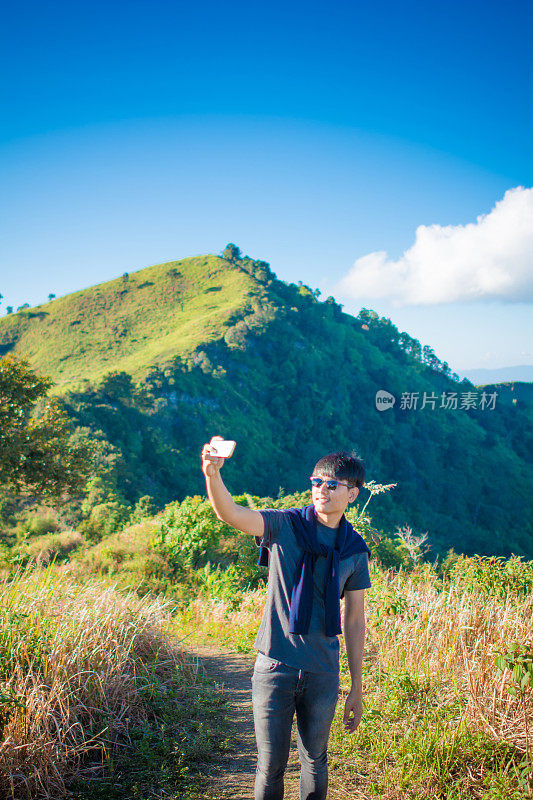 年轻的旅行者站在山上望着夕阳。