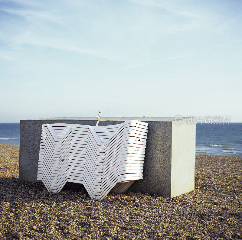 沙滩上叠放着的塑料椅，阳光明媚的日子