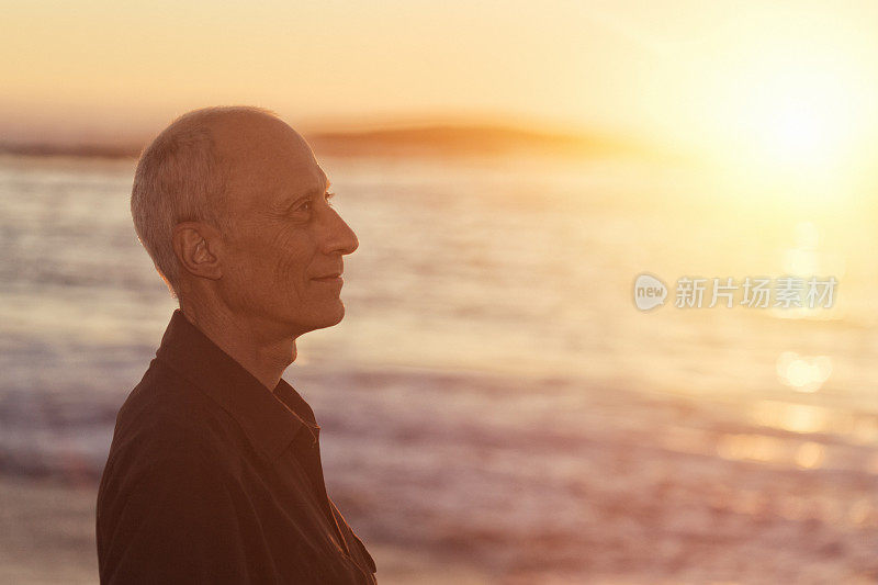 微笑成熟的男性摩托车手欣赏海滨日落