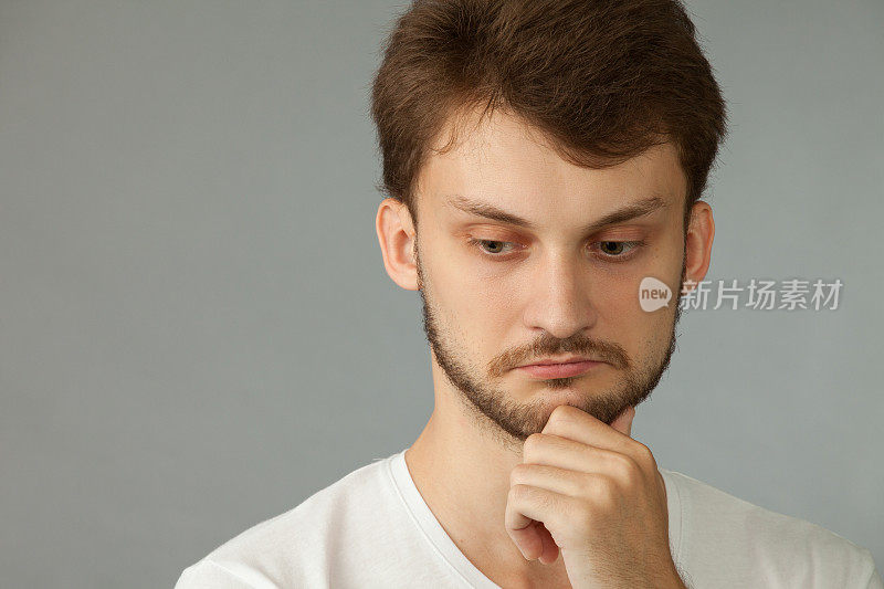 这是一幅27岁男子的肖像，他留着胡子，穿着白色t恤，背景是灰色的