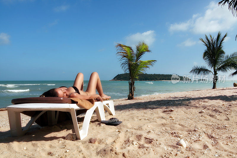 年轻的成年妇女放松和日光浴在海滩度假