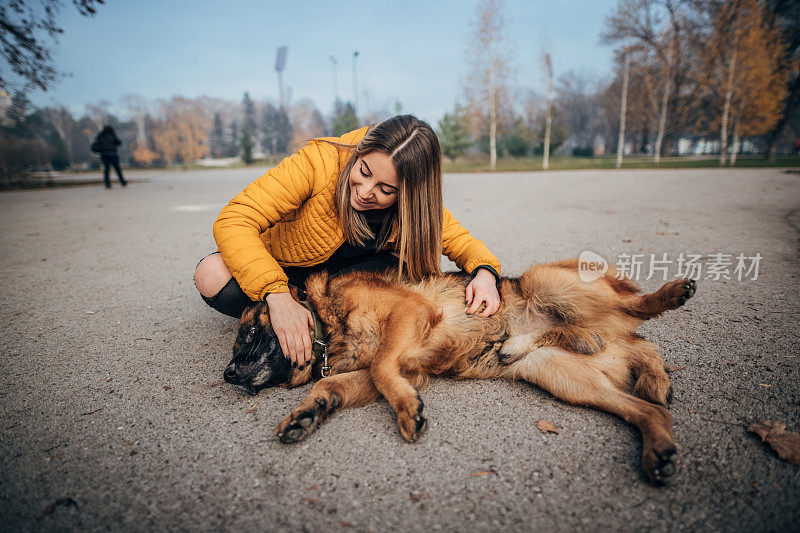 公园里有个年轻女人和一只德国牧羊犬