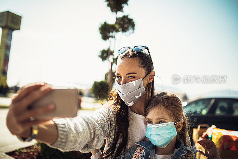 带着女儿戴着防护面具购物的女人