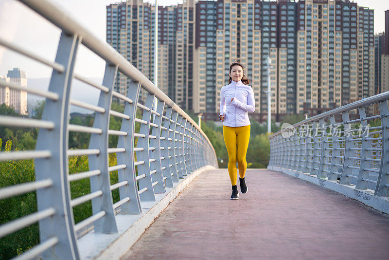 年轻的亚洲女人在城市街道上慢跑