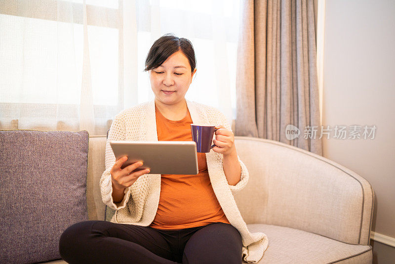 亚洲女人享受咖啡和看数字平板电脑