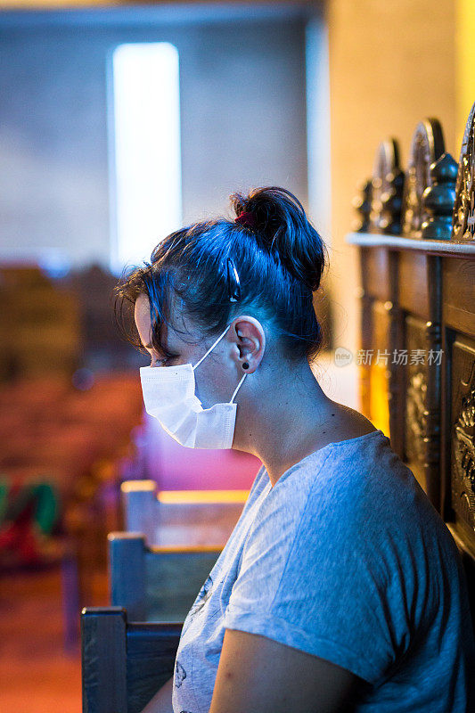 在教堂里祈祷的年轻妇女戴着防护面具
