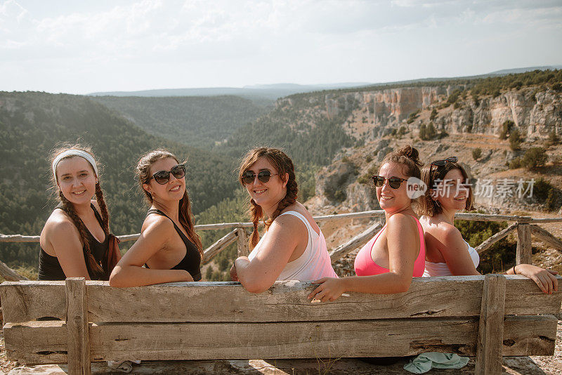 五个年轻的女人坐在山顶上看着摄像机