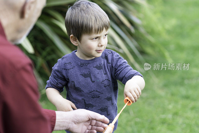 小男孩和爷爷在后院吹泡泡