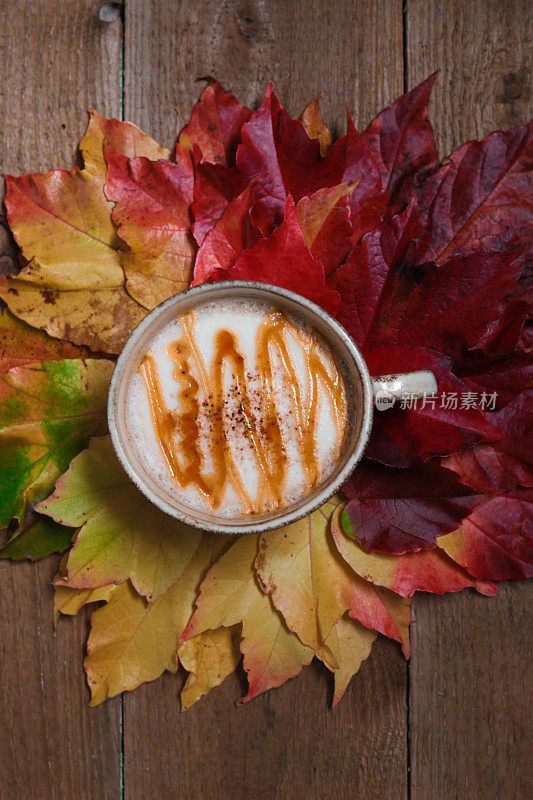 秋天的静物，一杯咖啡和五颜六色的枯叶在木板上