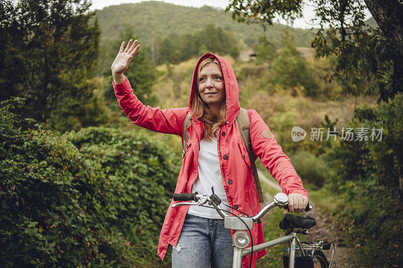 在雨中骑车——一位橙色头发、红色雨衣的年轻女子在雨中骑自行车