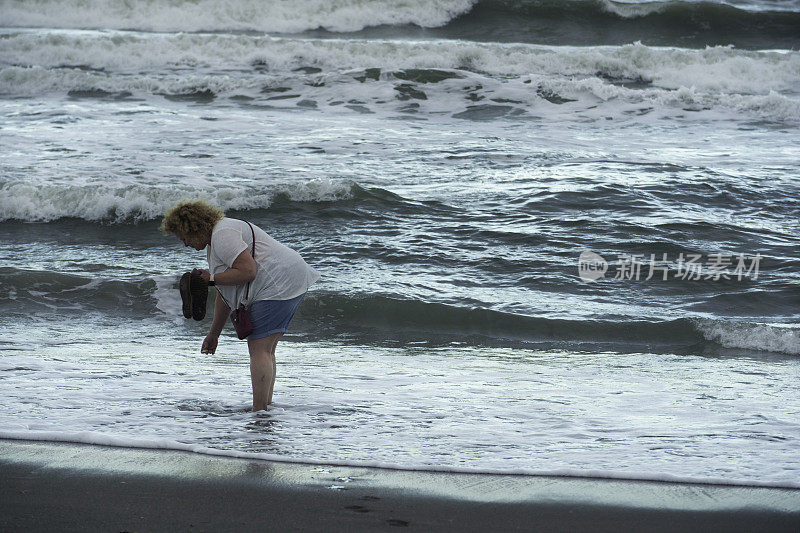 一个女人赤脚在海里找贝壳