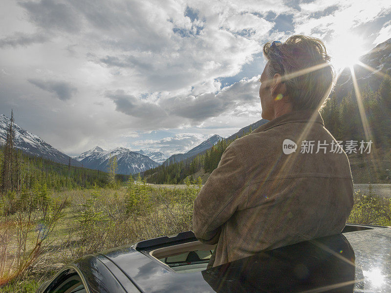 在山路上，一个男人穿过汽车天窗站起来