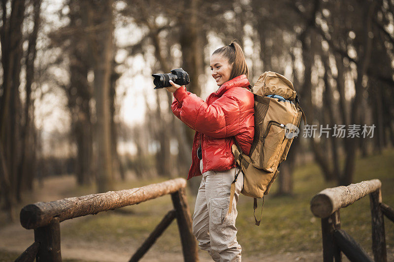 快乐的年轻女性徒步旅行者拍摄自然。女徒步旅行者在日出的山顶徒步旅行-年轻的女子背包上升到山顶。发现旅游目的地