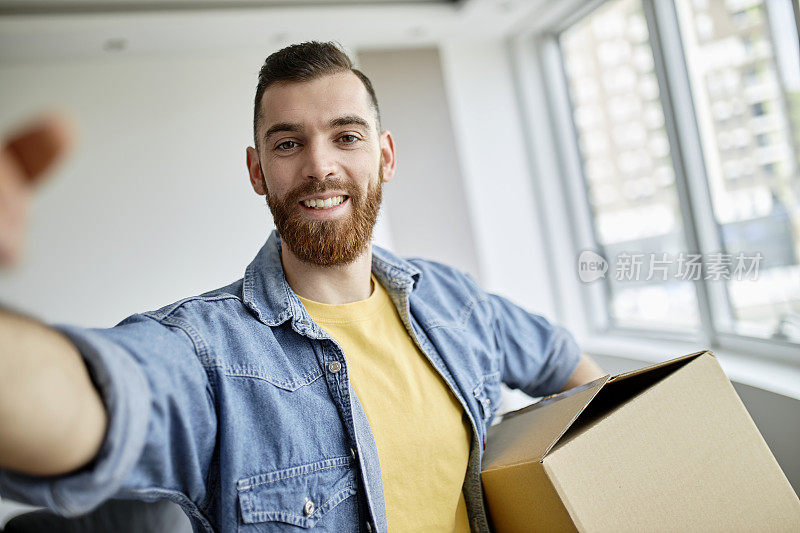 一个男人在他的新公寓里抱着纸板箱的自画像