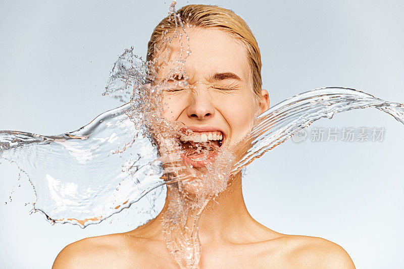 一个尖叫的女人的照片，脸上有水滴。年轻女子用干净的皮肤和水。温泉治疗。女孩用水洗她的身体。水和身体。皮肤和身体护理。