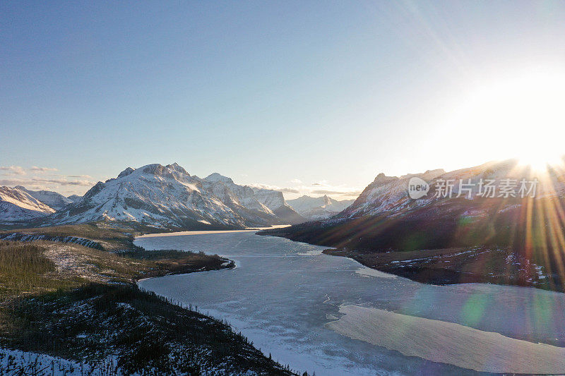 太阳落在蒙大拿冰雪湖周围的雪山后面