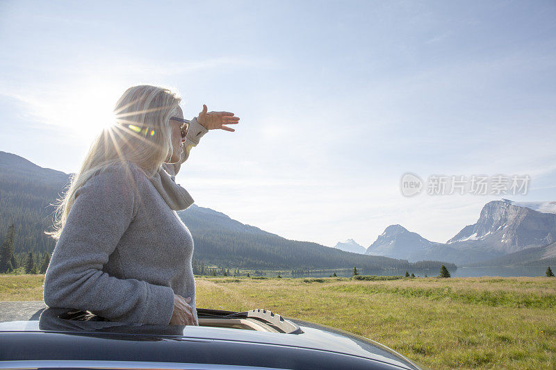 女人从汽车的天窗中站起来，望向窗外