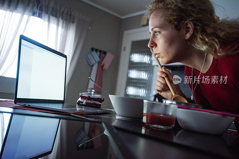 特写的女人看笔记本电脑，而准备一顿饭