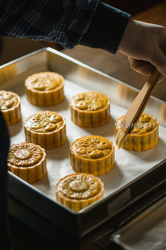 面包师在烤盘上用鸡蛋面团画自制月饼