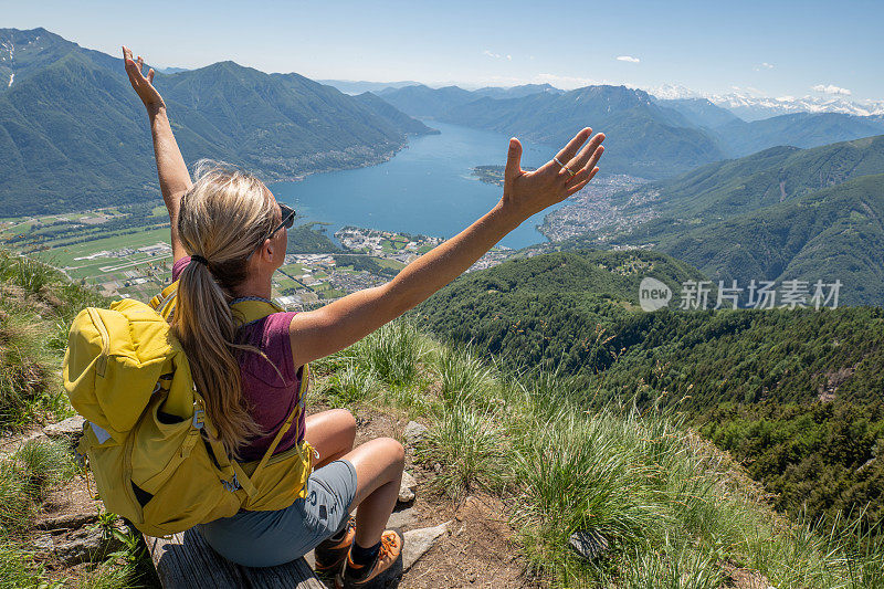 一个徒步旅行者双臂伸开站在山顶上