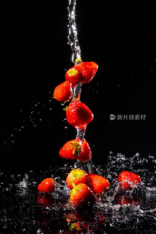 草莓落在水中，背景为黑色
