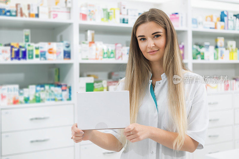 一名女药剂师展示着一盒白色的药品