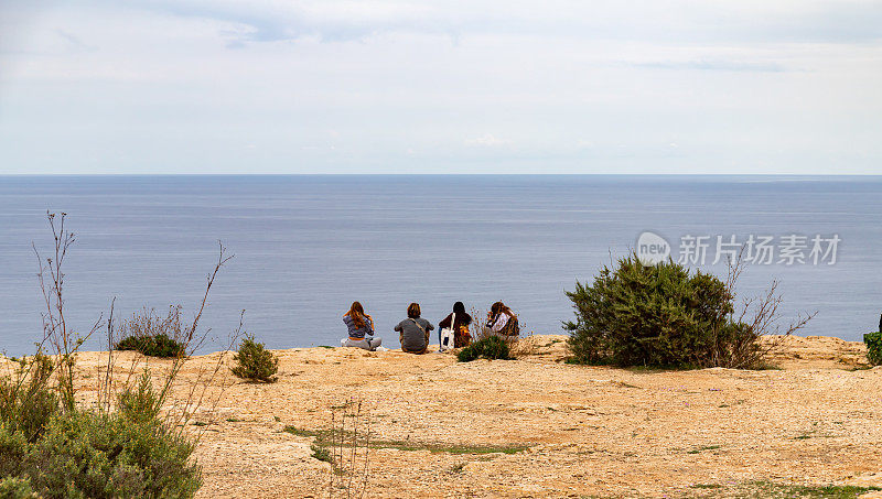 在巴利阿里群岛的福门特拉岛(Formentera)东南端，四个人向后坐着，眺望远方的大海。
