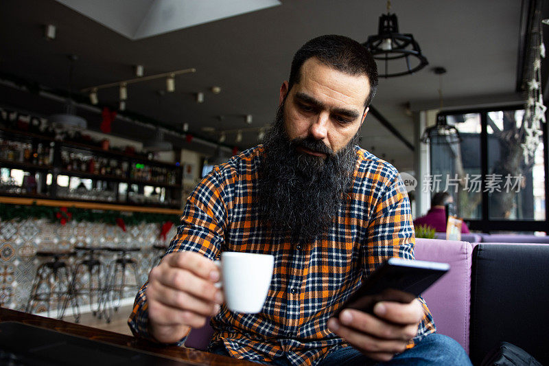 潮男同志在咖啡馆看新闻，用智能手机查收邮件