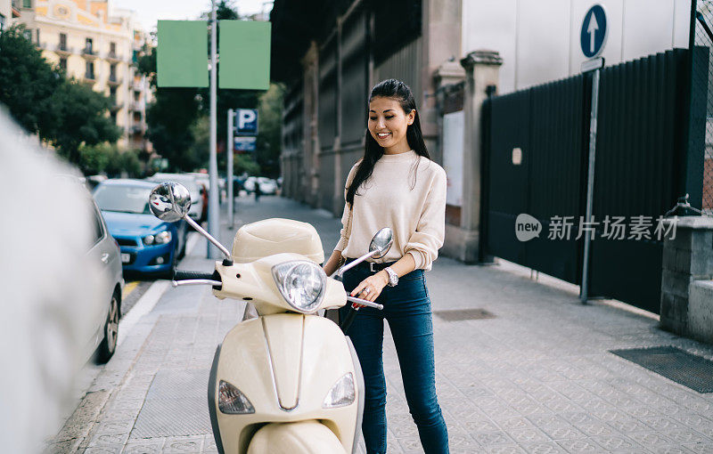 欢快的亚洲女性旅行者穿着休闲服装微笑着近租的老式助动车享受时间逃跑驾驶，快乐的嬉皮士游客20岁笑近复古摩托车