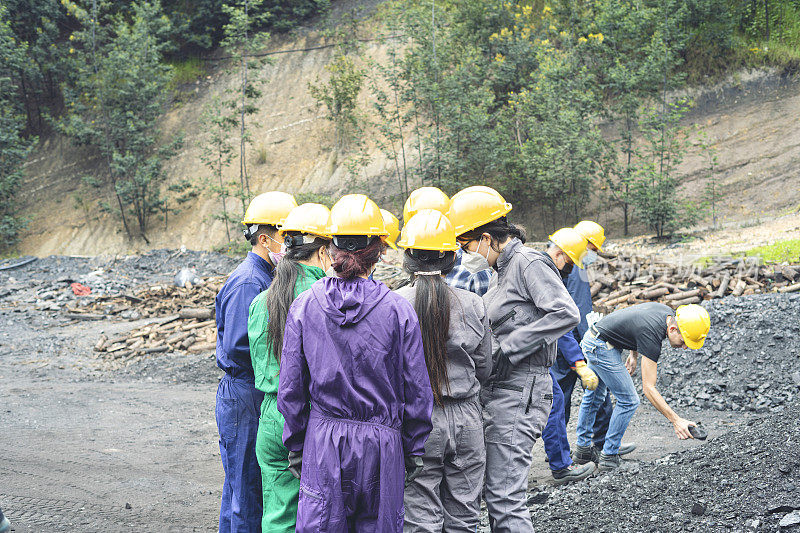 一群矿工聚集在矿井里看着煤块。