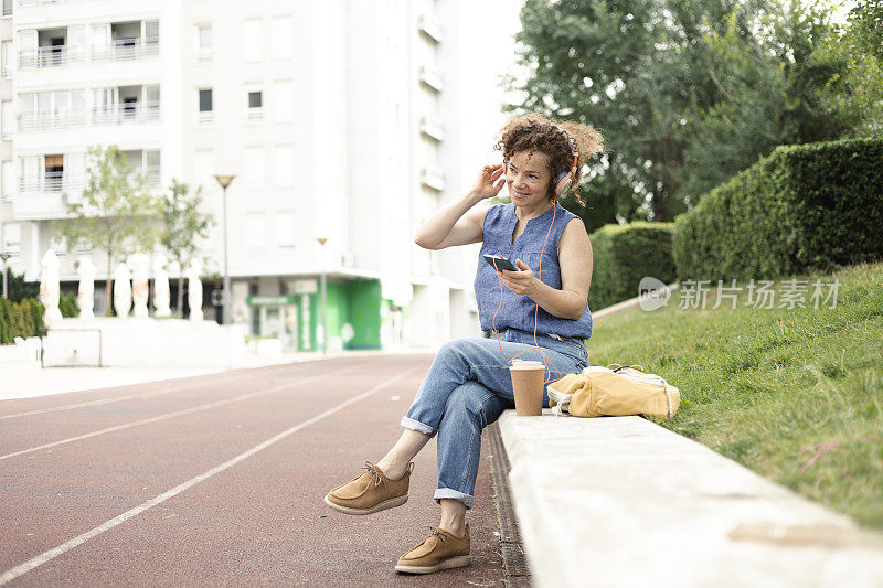 年轻女子坐在户外享受音乐