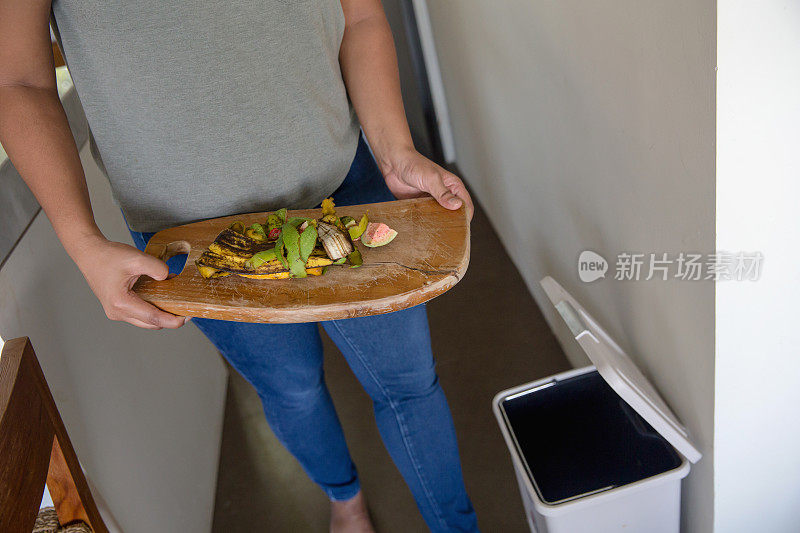 一名女子将有机食物垃圾扔进垃圾桶