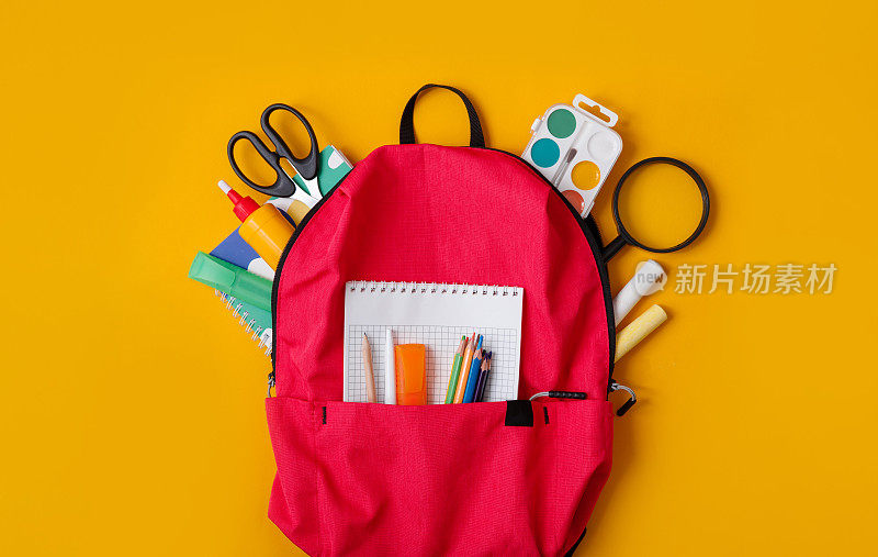 回到学校，书包与学校用品和文具在黄色的背景