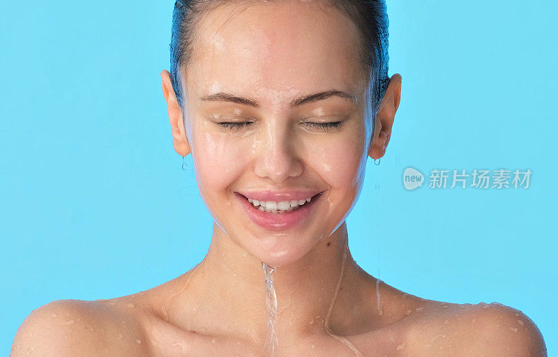 微笑的女性脸上有水。年轻快乐的女孩，脸上淌着水。女子用水洗干净的脸。