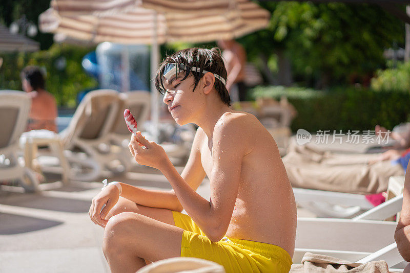 小男孩在度假村的游泳池里吃蛋筒冰淇淋