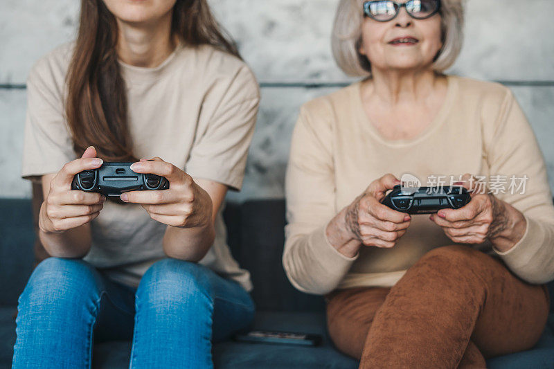 老女人和她的女儿玩游戏机，而花时间在一起的周末在家里的裁剪图像。微笑快乐的孩子。人们的生活方式。家庭幸福，童年快乐。