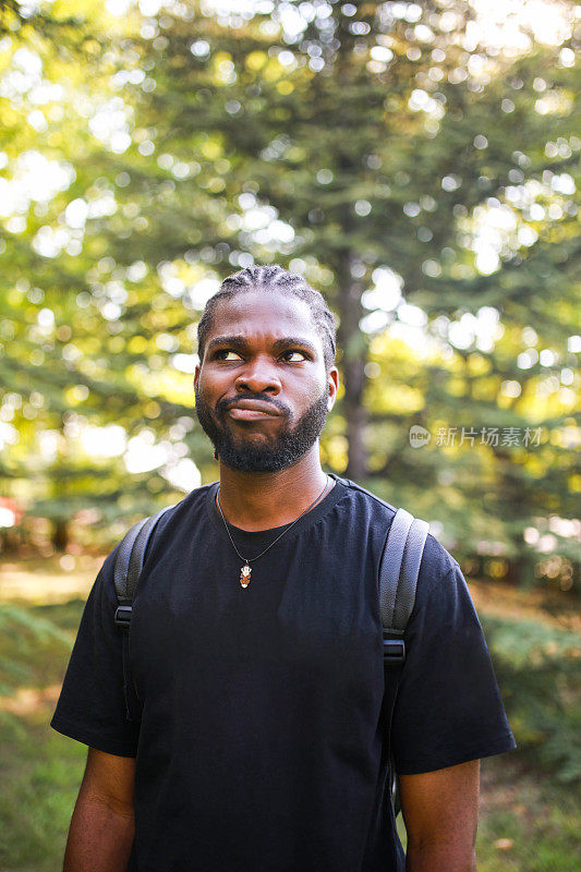 一个背着双肩包的非裔美国青年在大学花园