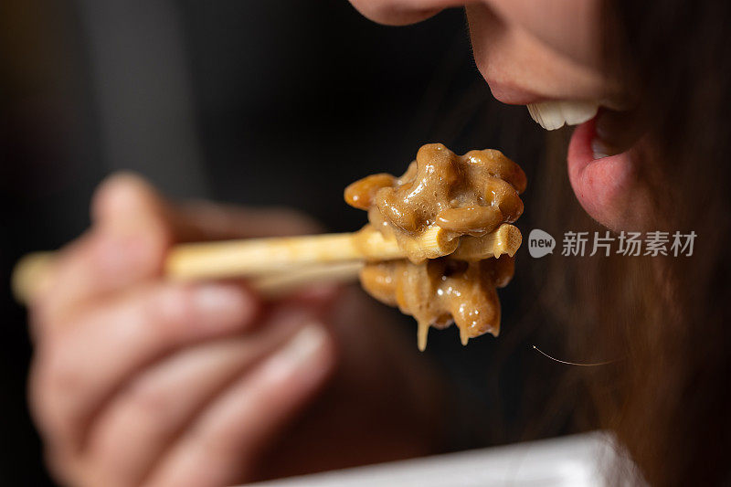 一个女人吃日本超级食物纳豆(发酵大豆)的特写