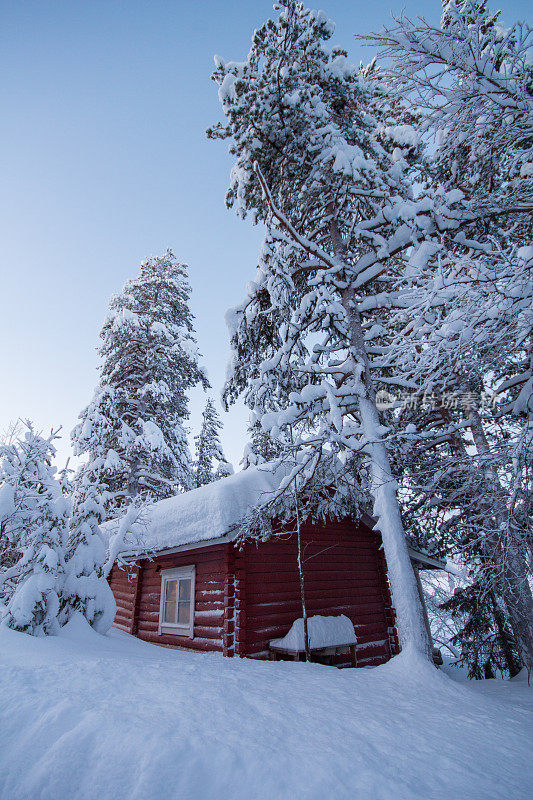一个晴朗的冬日，芬兰拉普兰雪林中的木屋