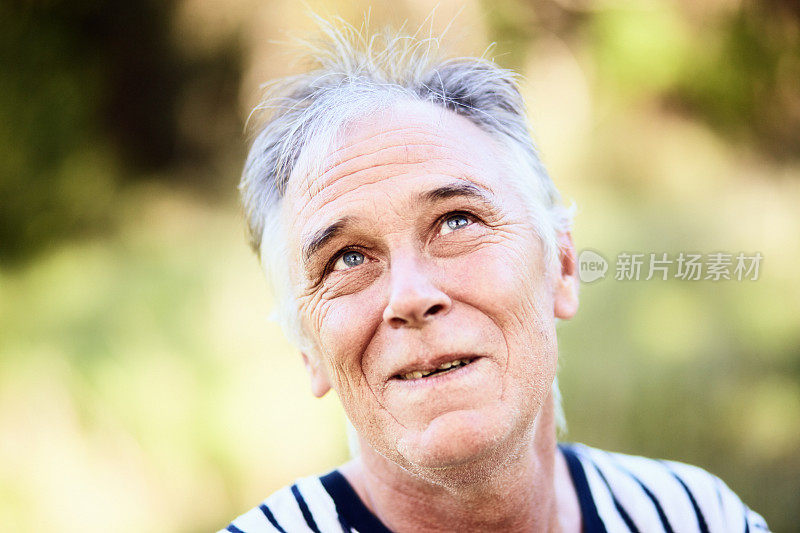 成熟的男人站在户外抬起头，脸上带着一种被逗乐的不确定的表情