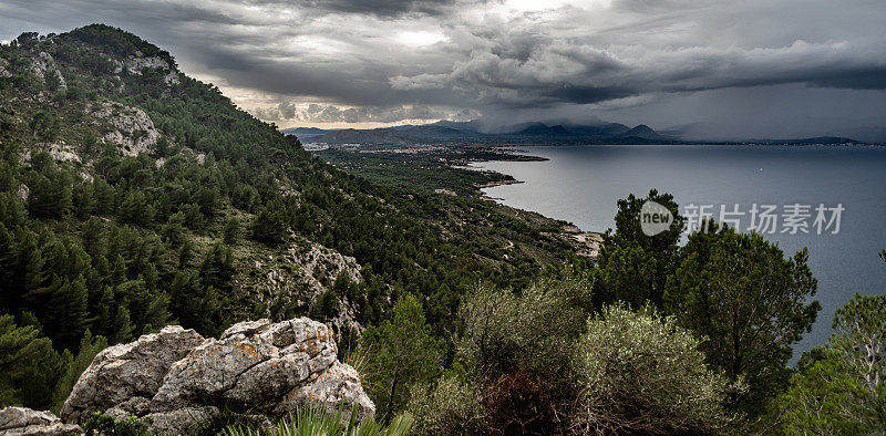 地中海的风景，在巴利阿里群岛的阿尔库迪亚。西班牙，西班牙的风景。美丽的自然和高山岩石。天空中乌云密布。周围有森林和沙滩