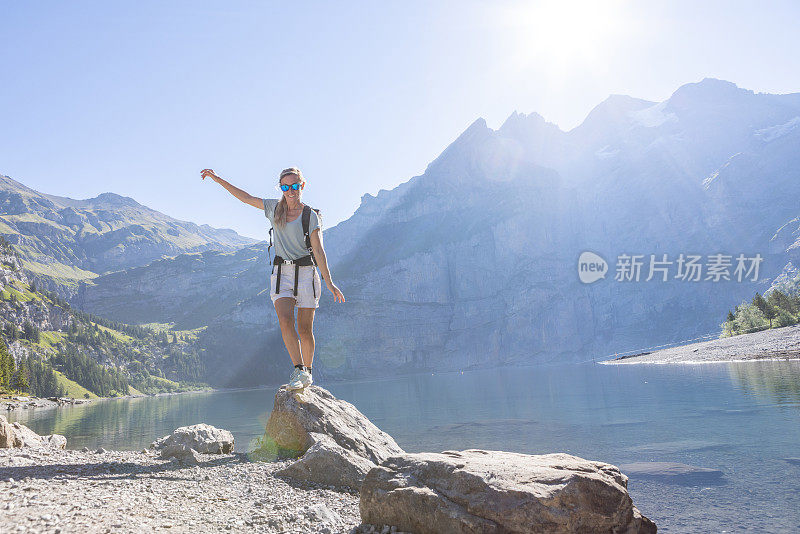 一名女子在高山湖边的岩石间跳跃