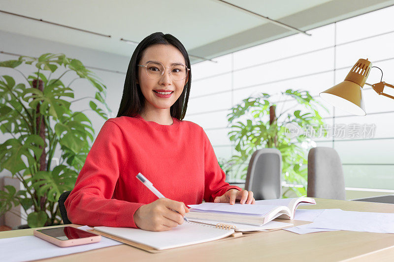 咖啡店里，女人用铅笔在笔记本上写字。在咖啡店户外工作的妇女。