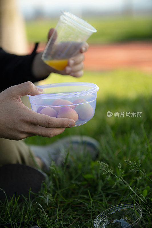 年轻人拿着一个塑料杯在外面。