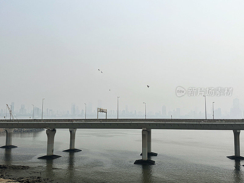 印度孟买班德拉-沃利海路(拉吉夫甘地海路)的特写图片，混凝土、斜拉桥、海水、八车道高架桥、柱子、烟雾