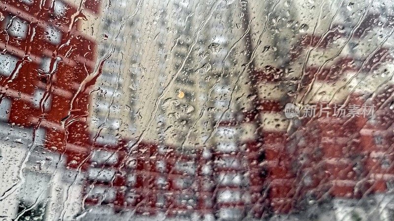城市里，雨滴落在汽车挡风玻璃上，潺潺流水